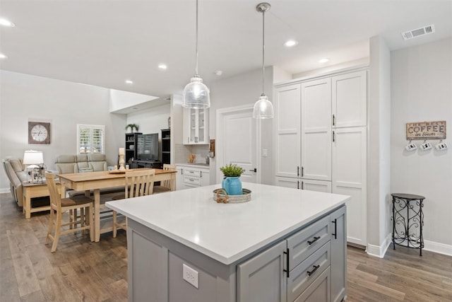 kitchen featuring light countertops, white cabinetry, wood finished floors, and a kitchen island