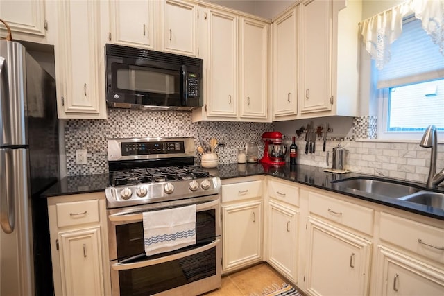 913 Fowzer St, Taylor, TX 76574 - kitchen featuring a sink, decorative backsplash, dark countertops, and stainless steel appliances