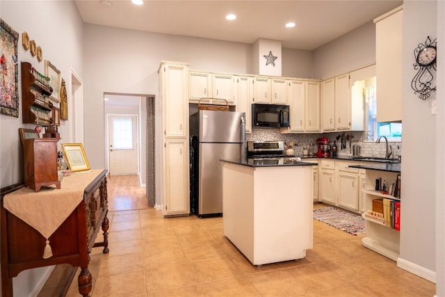 913 Fowzer St, Taylor, TX 76574 - kitchen with dark countertops, appliances with stainless steel finishes, a sink, backsplash, and a kitchen island