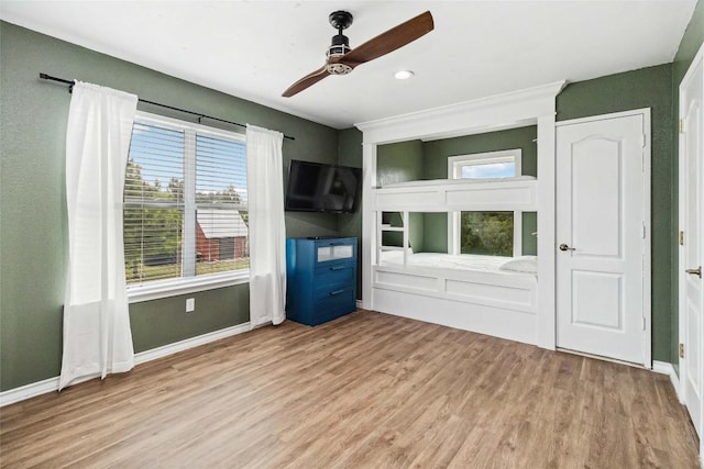 unfurnished living room featuring baseboards, a ceiling fan, and wood finished floors
