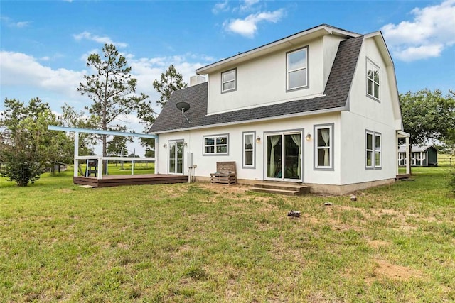 rear view of property with roof with shingles, a lawn, a deck, entry steps, and stucco siding