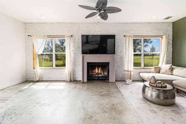 living room featuring visible vents, a ceiling fan, concrete flooring, and a lit fireplace