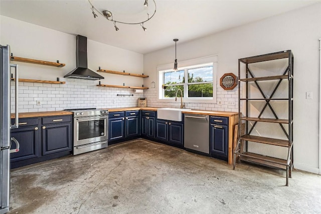 kitchen with wall chimney range hood, open shelves, appliances with stainless steel finishes, a sink, and wood counters