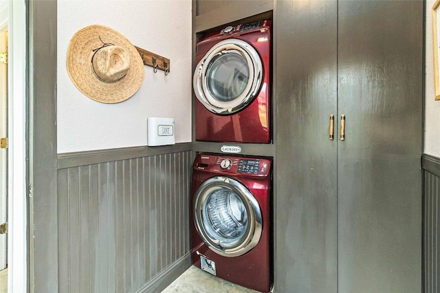 laundry area featuring laundry area, stacked washing maching and dryer, and a wainscoted wall