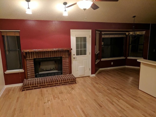 1502 Stratford Dr, Killeen, TX 76549 - unfurnished living room with a fireplace, wood finished floors, ceiling fan, a textured wall, and a chandelier