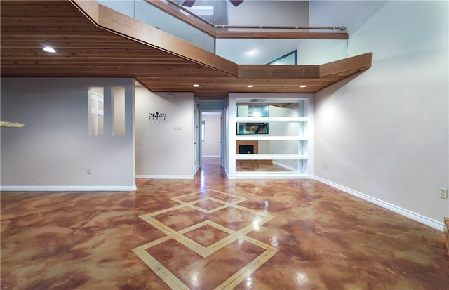 interior space with a ceiling fan, baseboards, a high ceiling, and finished concrete floors