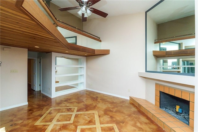 unfurnished living room with baseboards, a ceiling fan, finished concrete floors, and a tile fireplace