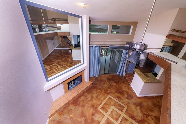 interior space with concrete floors, ceiling fan, and a fireplace