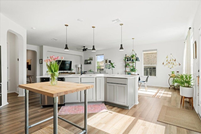 kitchen with ceiling fan, decorative light fixtures, arched walkways, light countertops, and light wood-style floors