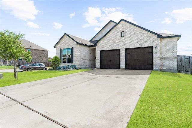 french country style house featuring fence, brick siding, a garage, a front yard, and driveway