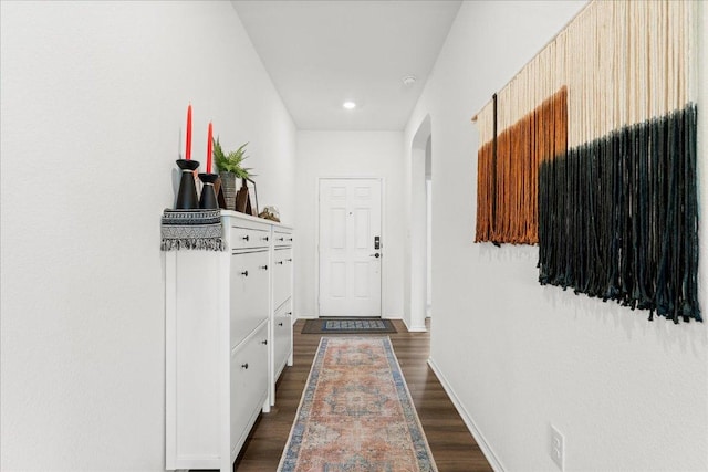 interior space featuring arched walkways, baseboards, recessed lighting, and dark wood-type flooring
