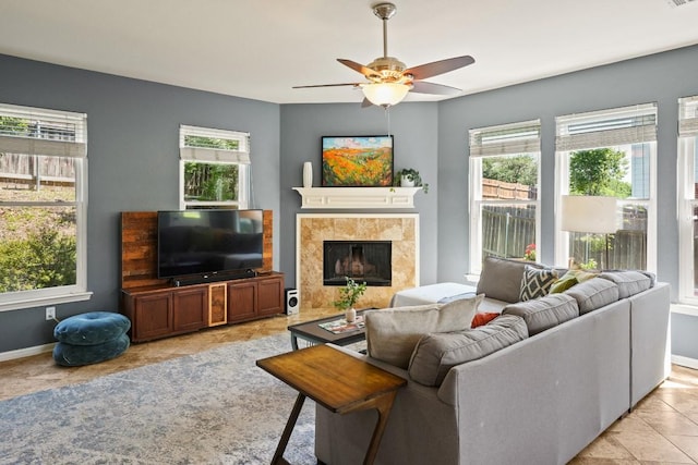 living room featuring a ceiling fan, a fireplace, light tile patterned flooring, and plenty of natural light