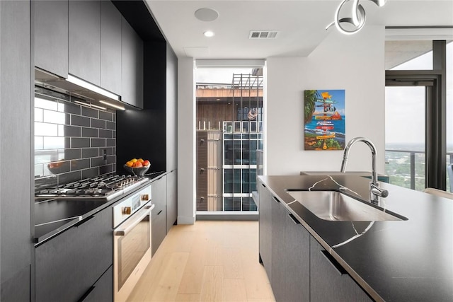 44 E Ave Unit 2907, Austin, TX 78701 - kitchen featuring a sink, tasteful backsplash, visible vents, dark countertops, and appliances with stainless steel finishes