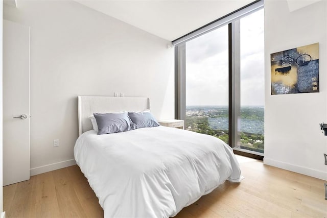 44 E Ave Unit 2907, Austin, TX 78701 - bedroom featuring expansive windows, baseboards, and light wood-type flooring