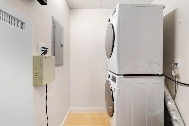 44 E Ave Unit 2907, Austin, TX 78701 - laundry area featuring light wood-style flooring, laundry area, stacked washing maching and dryer, electric panel, and baseboards