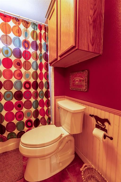 511 Shadywood Ln, Dripping Springs, TX 78620 - bathroom with toilet, a wainscoted wall, a shower with curtain, and tile patterned floors