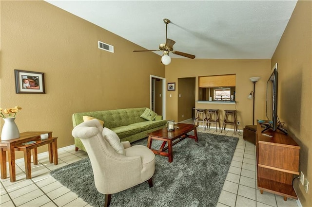 living area featuring light tile patterned floors, a ceiling fan, visible vents, a textured wall, and vaulted ceiling