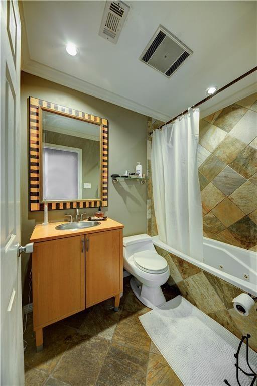 bathroom featuring crown molding, toilet, tiled shower / bath, and visible vents