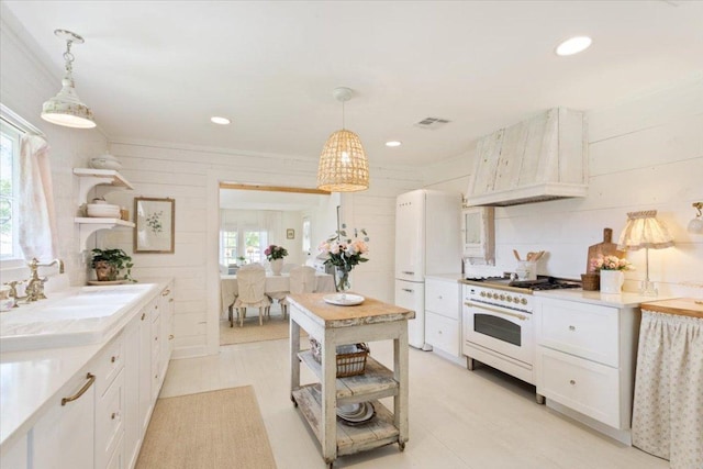 kitchen with a sink, custom exhaust hood, open shelves, and white appliances