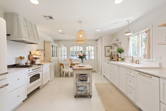 kitchen featuring a sink, custom exhaust hood, white cabinetry, light countertops, and white range with gas stovetop