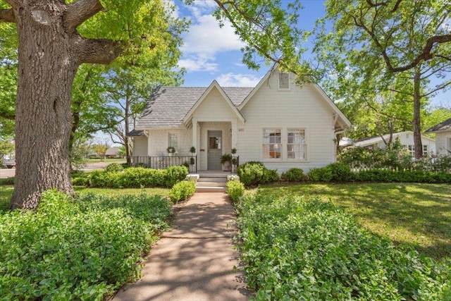 bungalow-style home with a shingled roof and a front yard