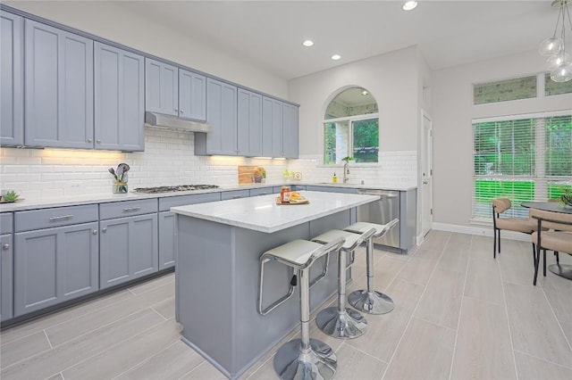 kitchen featuring a sink, a breakfast bar, light countertops, appliances with stainless steel finishes, and recessed lighting