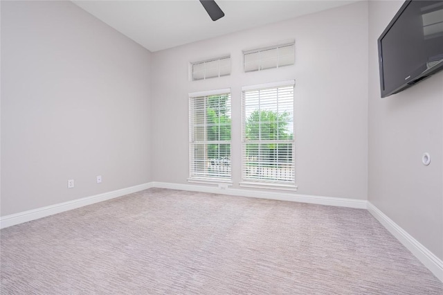 carpeted empty room with baseboards and a ceiling fan