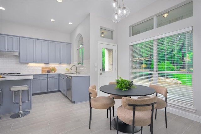 14912 Swallow Tailed Kite Dr, Austin, TX 78738 - kitchen with gray cabinets, a sink, light countertops, backsplash, and hanging light fixtures