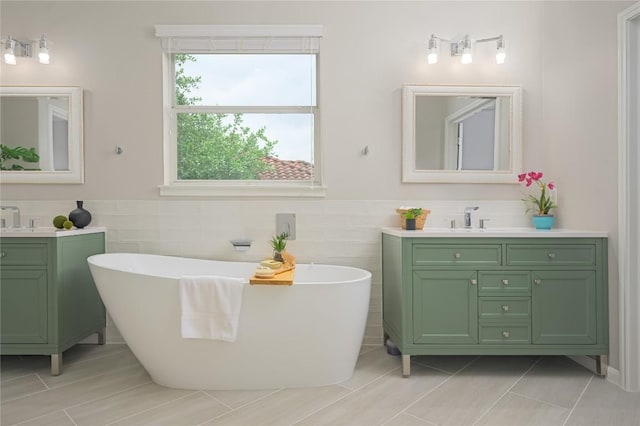 14912 Swallow Tailed Kite Dr, Austin, TX 78738 - bathroom featuring tile walls, two vanities, a freestanding bath, wainscoting, and tile patterned floors