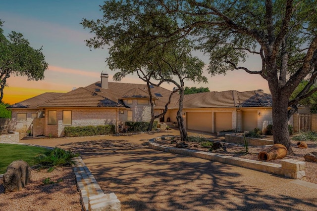 26302 Countryside Dr, Spicewood, TX 78669 - view of front of property with a chimney, an attached garage, a tiled roof, and stone siding