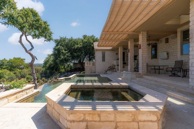 pool with an in ground hot tub and a patio