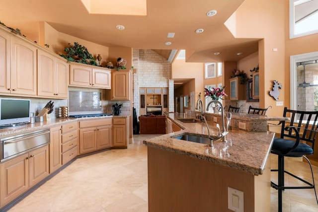 26302 Countryside Dr, Spicewood, TX 78669 - kitchen with a breakfast bar area, a warming drawer, light stone countertops, decorative backsplash, and gas cooktop