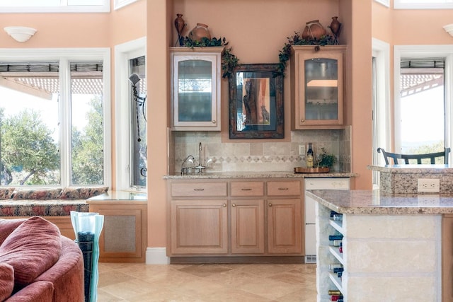 bar with light tile patterned floors, wet bar, white dishwasher, and decorative backsplash