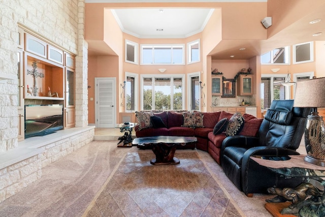 carpeted living area with a wealth of natural light, crown molding, and a towering ceiling