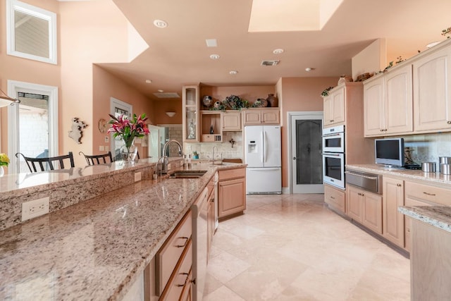kitchen with white refrigerator with ice dispenser, a warming drawer, backsplash, and a sink