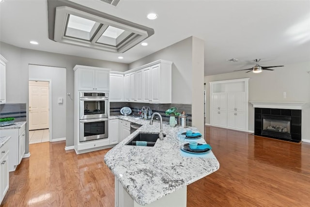 105 Saddle Trl, Georgetown, TX 78633 - kitchen featuring a peninsula, stainless steel double oven, white cabinetry, backsplash, and light wood-style floors
