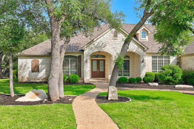 110 Woodall Dr, Georgetown, TX 78628 - view of front facade with french doors, stone siding, a shingled roof, and a front yard