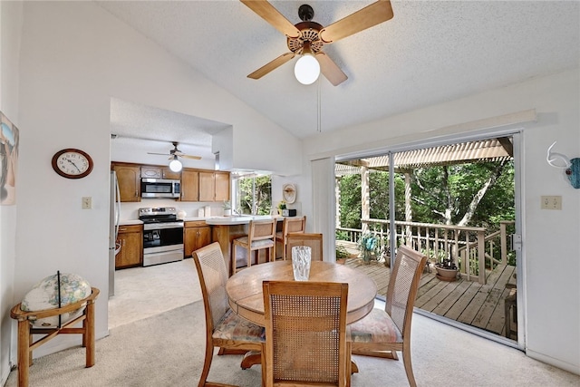 dining area with ceiling fan, a textured ceiling, light colored carpet, and high vaulted ceiling