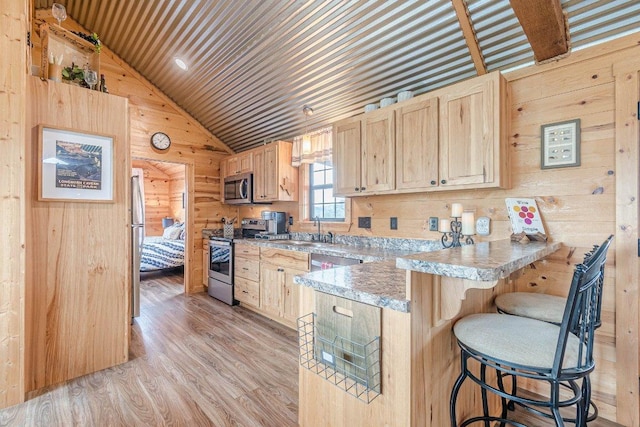 770 Stanton Rd, Johnson City, TX 78636 - kitchen with stainless steel appliances, wood walls, light brown cabinetry, a sink, and a peninsula