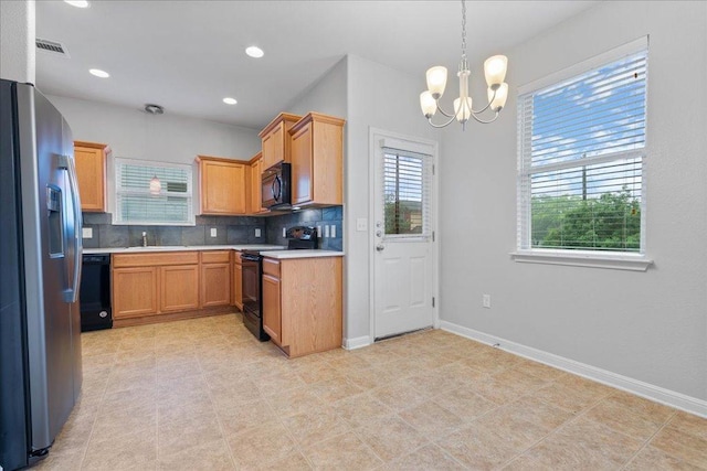kitchen featuring black appliances, a sink, a chandelier, light countertops, and decorative backsplash