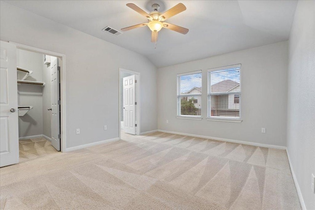 unfurnished bedroom featuring carpet, vaulted ceiling, a walk in closet, baseboards, and connected bathroom