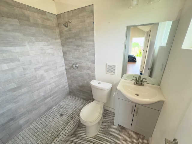full bath featuring toilet, vanity, visible vents, tile patterned flooring, and tiled shower
