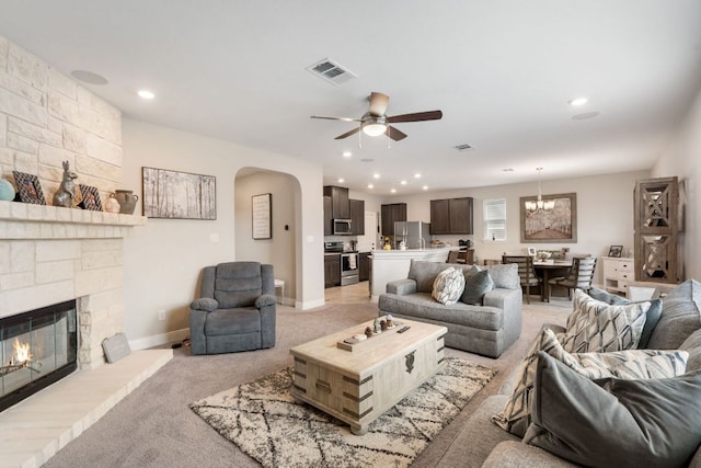 130 Mcginnis Trl, Kyle, TX 78640 - living area with ceiling fan with notable chandelier, baseboards, a stone fireplace, arched walkways, and light colored carpet
