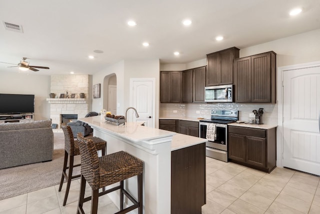 130 Mcginnis Trl, Kyle, TX 78640 - kitchen with dark brown cabinets, ceiling fan, visible vents, arched walkways, and appliances with stainless steel finishes
