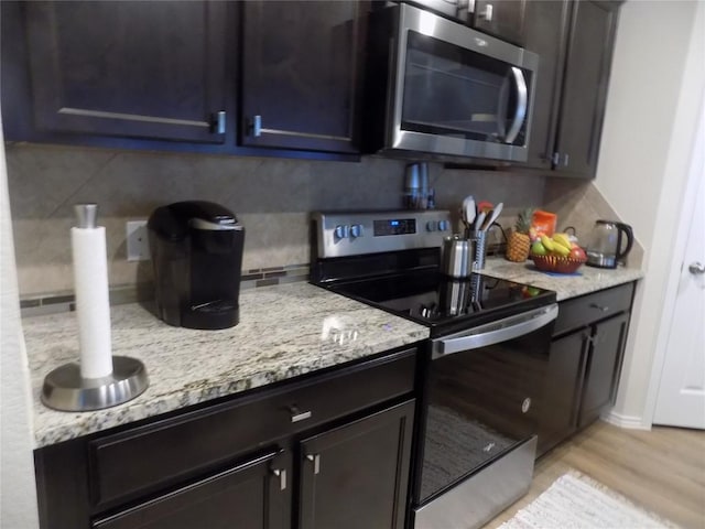 124 Rearden Blvd, Jarrell, TX 76537 - kitchen featuring appliances with stainless steel finishes, tasteful backsplash, light stone countertops, and light wood-style floors