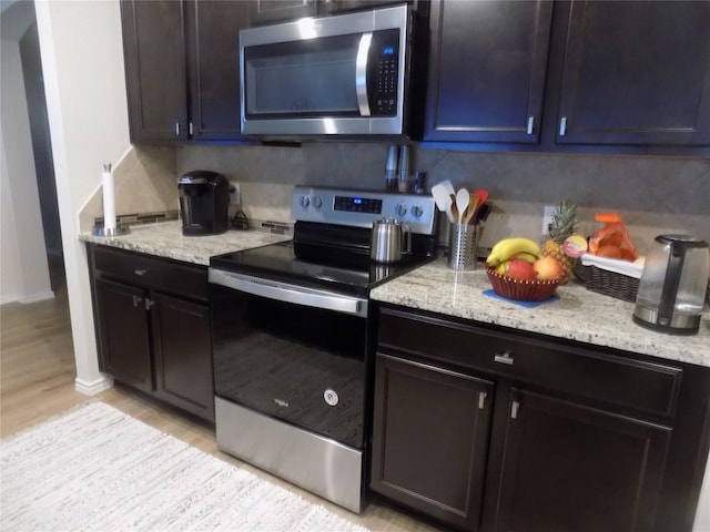 124 Rearden Blvd, Jarrell, TX 76537 - kitchen featuring appliances with stainless steel finishes, backsplash, light stone countertops, light wood-style floors, and baseboards
