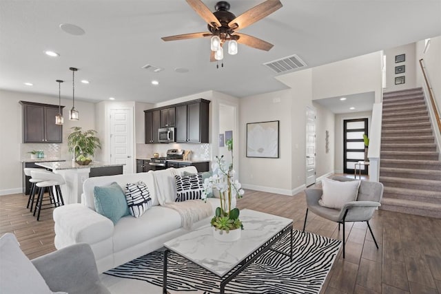 living room with wood finished floors, visible vents, and baseboards