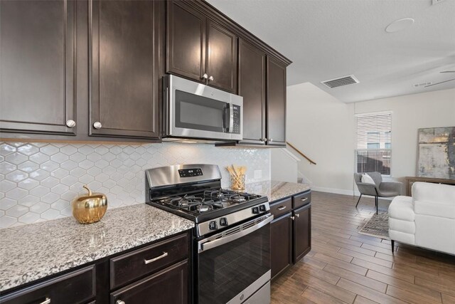 kitchen featuring dark brown cabinets, open floor plan, visible vents, baseboards, and appliances with stainless steel finishes
