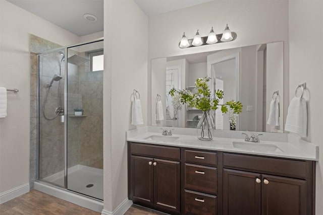 bathroom with wood finished floors, baseboards, a stall shower, and a sink