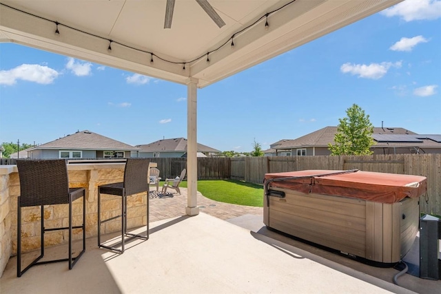 view of patio with outdoor dry bar, a hot tub, a residential view, and a fenced backyard